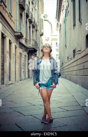 schöne blonde Frau anhören von Musik in der Stadt Stockfoto