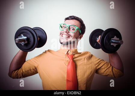 lustige verrückte junge Mann Gewichtheben auf grauem Hintergrund Stockfoto