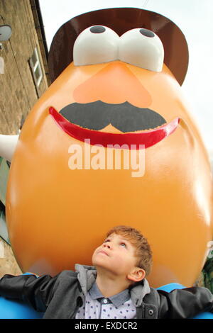 Belper, Derbyshire, UK. 12. Juli 2015. Three-Year-Old Darwyn Reed aus Belper blickt bis auf eine riesige Mr. Potato Head, die neu in einer Stadt Derbyshire erschienen ist. 7ft Fiberglas Statue wurde im Jahr 2001 von seiner Partnerstadt, Pawtucket, Rhode Island, USA Belper begabt. Nach wird ein "Monstrum" von einigen Einheimischen genannt, machte die trennende Charakter landesweit Schlagzeilen. Es war verwüstet und verbannt. Jetzt wurde die Knolle von einer lokalen Jugendgruppe herausgeputzt und enthüllt Belpers Food Festival heute. Bildnachweis: Deborah Vernon/Alamy Live-Nachrichten Stockfoto