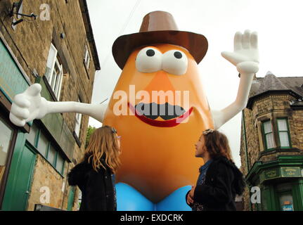 Belper, Derbyshire, UK. 12. Juli 2015. Brii Matheson, 8, (l) und ihre Schwester Norden, 6, von Belpergaze bis zu einer riesigen Mr. Potato Head, die neu in einer Stadt Derbyshire erschienen ist. 7ft Fiberglas Statue wurde im Jahr 2001 von seiner Partnerstadt, Pawtucket, Rhode Island, USA Belper begabt. Nach wird ein "Monstrum" von einigen Einheimischen genannt, machte die trennende Charakter landesweit Schlagzeilen. Es war verwüstet und verbannt. Jetzt wurde die Knolle von einer lokalen Jugendgruppe herausgeputzt und enthüllt Belpers Food Festival heute. Bildnachweis: Deborah Vernon/Alamy Live-Nachrichten Stockfoto