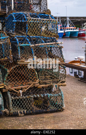 Ein Stapel von Fischen Gatter (Hummer und Krabben Töpfe) im Hafen von Bridlington. Angelboote/Fischerboote im Hintergrund Stockfoto