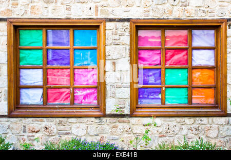 Zwei Fenster in einer Mauer, die von bunten Papier abgedeckt Stockfoto