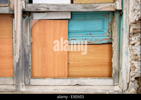 Ein Fenster mit Brettern vernagelt von Holzplatten in einem alten Haus Stockfoto