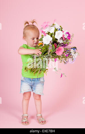 Porträt Kleinkind Mädchen mit Blumenstrauß Garten Blumen auf rosa Hintergrund Stockfoto