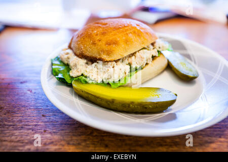 Ein Thunfisch-Salat-Sandwich mit Roamine Salat auf eine Torta Rollen auf einer kleinen Platte an einem Schreibtisch Stockfoto