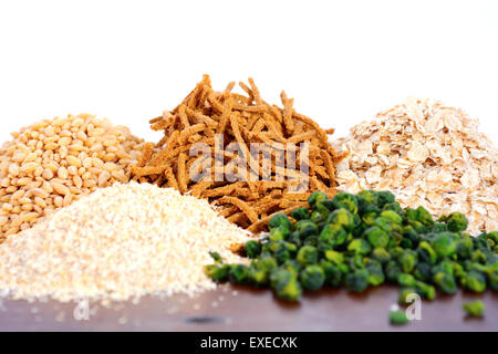 Stapel von gesunden hohe Faser Präbiotikum Körner einschließlich Weizen-Kleie-Müsli, Haferflocken und Graupen auf rustikalen dunklen Holztisch Stockfoto