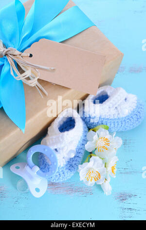 Baby-Dusche seine junge natürliche Verpackung Geschenk mit Geschenk-Box, baby-Schühchen und dummy auf blass blauen shabby chic rustikalen Holztisch. Stockfoto