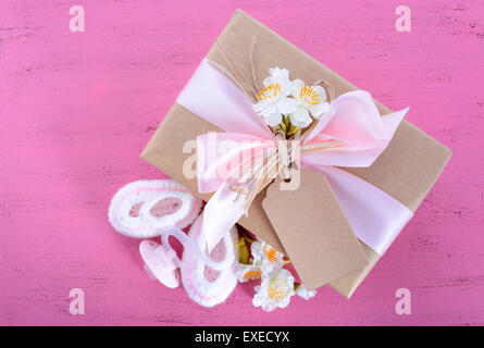 Baby-Dusche seine Mädchen natürliche Verpackung Geschenk mit Geschenk-Box, baby-Schühchen und dummy auf rosa shabby chic rustikalen Holztisch. Stockfoto