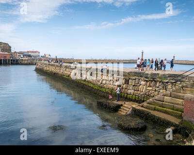 Urlauber auf Tate Hill Pier Whitby North Yorkshire, die Pier erbaute A.D.1190 ist eines der ältesten in der Welt Stockfoto