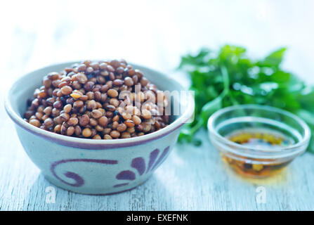 Linsen in Schüssel geben und auf einem Tisch Stockfoto