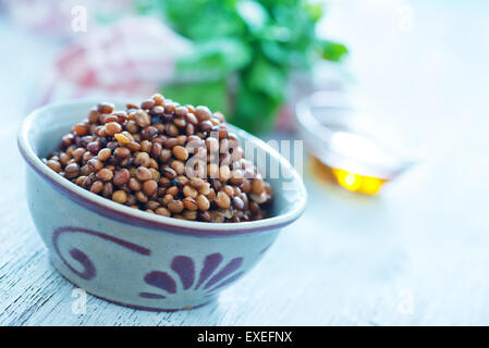 Linsen in Schüssel geben und auf einem Tisch Stockfoto