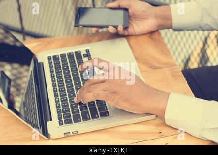Asiatische indische Geschäftsmann mit Smartphone und Laptop-Computer in Outdoor-Cafeteria. Stockfoto