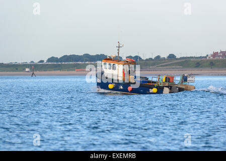 Ein Fischerboot Schiff Segeln aus Bridlington in den frühen Morgenstunden mit Bridlington Strand im Hintergrund Stockfoto