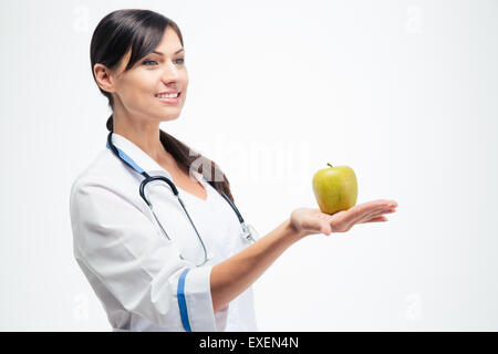 Glückliche junge Ärztin hält Apfel isoliert auf einem weißen Hintergrund. Wegschauen Stockfoto
