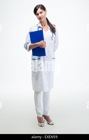 In voller Länge Portrait von einer fröhlichen Ärztin mit Zwischenablage stehen isoliert auf weißem Hintergrund Stockfoto