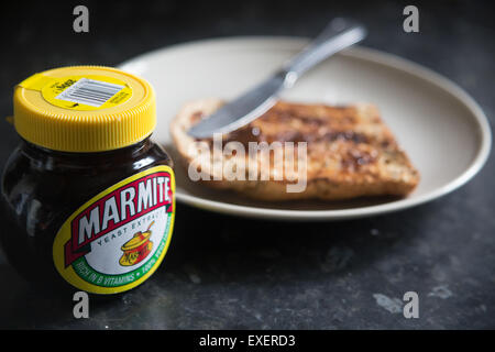 Ein Glas Marmite-Hefeextrakt neben Toast auf einem Teller, das ein klassisches britisches Frühstück und die kultige „Love IT or Hate IT“-Kultur veranschaulicht Stockfoto