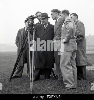 Historische, der 1950er Jahre geeignet Foto zeigt eine Gruppe von männlichen Vermesser aussen mit einem Theodolit, eine Präzision, Messgerät, für die topographische Vermessung verwendet. Stockfoto