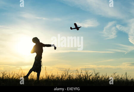 Junge werfen ein Modellflugzeug bei Sonnenuntergang. Silhouette Stockfoto