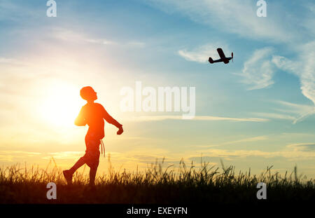 Junge werfen ein Modellflugzeug bei Sonnenuntergang. Silhouette Stockfoto