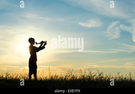Junge werfen ein Modellflugzeug bei Sonnenuntergang. Silhouette Stockfoto
