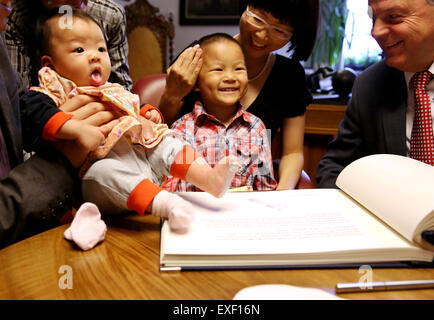 Freiberg / Deutschland. 9. Juli 2015. Die Geschwister aus China den Namen "Berg", das Mädchen und ihr Bruder "Frei" mit ihren Eltern Huixian Yang (C) und Hong She und Bürgermeister Bernd-Erwin Schramm (R) vor das silberne Buch der Stadt Freiberg, Deutschland, 9. Juli 2015 zu sitzen. Die Eltern der Kinder haben trafen sich während seines Studiums an der Freiberger Universität. Zu Ehren ihrer Gastgeber-Stadt beschlossen die Eltern, ihre Kinder nach der Stadt Freiberg zu benennen. Foto: Jan Woitas/Dpa/Alamy Live News Stockfoto