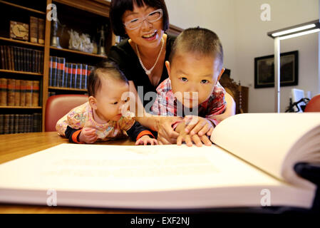 Freiberg / Deutschland. 9. Juli 2015. Die Geschwister aus China den Namen "Berg", das Mädchen und ihr Bruder "Frei" mit ihrer Mutter Huixian Yang (C) vor das silberne Buch der Stadt Freiberg, Deutschland, 9. Juli 2015 zu sitzen. Die Eltern der Kinder haben trafen sich während seines Studiums an der Freiberger Universität. Zu Ehren ihrer Gastgeber-Stadt beschlossen die Eltern, ihre Kinder nach der Stadt Freiberg zu benennen. Foto: Jan Woitas/Dpa/Alamy Live News Stockfoto