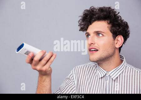 Mann hält TV remote über grauen Hintergrund Stockfoto