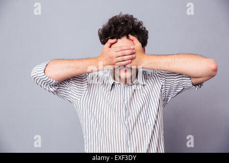 Manndeckung seine Augen mit Händen auf grauem Hintergrund Stockfoto