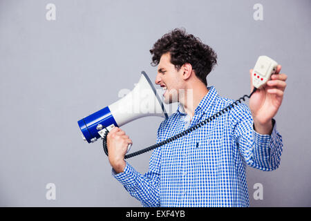 Legerer Mann Regie Megaphon an sich über grauen Hintergrund Stockfoto