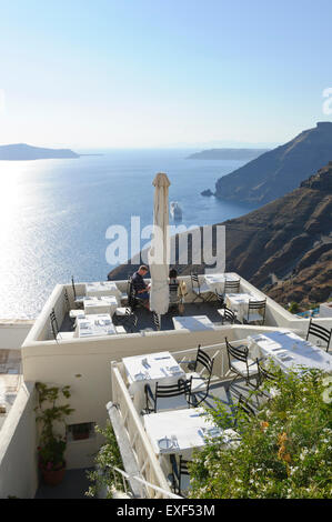 Ein junges Paar, Abendessen in einem Restaurant auf die Caldera mit dem Meer, Santorini, Griechenland. Stockfoto