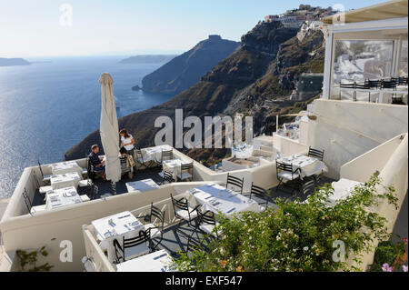 Ein junges Paar, Abendessen in einem Restaurant auf die Caldera mit dem Meer, Santorini, Griechenland. Stockfoto