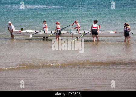 Frauen-Ruderer heben Boot aus dem Meer bei Swanage Regatta im Juni Stockfoto