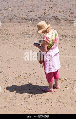 Frau mit Iphone am Strand von Swanage im Juni Stockfoto