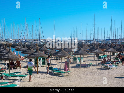 Leben am Strand mit Sonnenschirme, Liegestühle und Masten in der Marina an einem sonnigen Sommertag Stockfoto