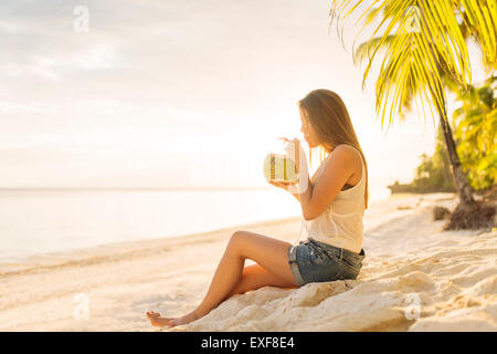 Junge Frau trinkt frische Kokosmilch am Strand von Anda, Provinz Bohol, Philippinen Stockfoto