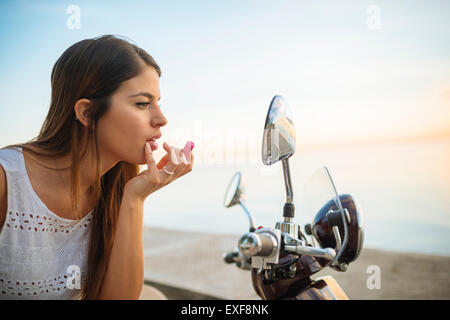 Junge Frau Auftragen von Lippenstift in Motorrad Spiegel, Manila, Philippinen Stockfoto