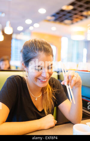 Junge Frau, die das Essen mit Stäbchen in Restaurant, Manila, Philippinen Stockfoto