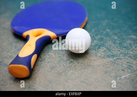 Tischtennis-Schläger und Ball auf abgenutzten Tisch Stockfoto