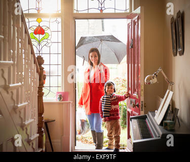 Mutter und Sohn, die Ankunft am Eingangstür des Hauses am regnerischen Tag, Porträt Stockfoto