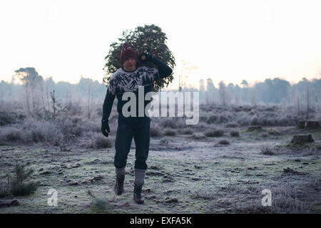 Holzfäller mit Tanne über seine Schulter in Waldlichtung Stockfoto