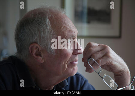 Senior woman, hält Brillen, Blick aus Fenster Stockfoto