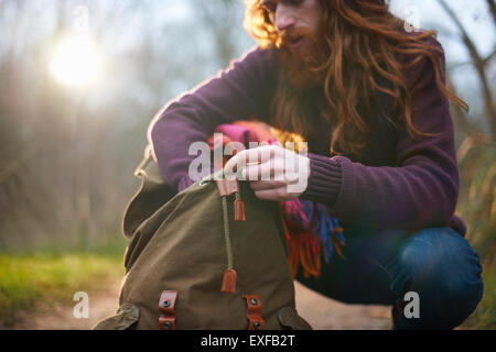 Mann kniet, Wühlen im Rucksack Stockfoto