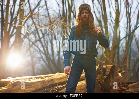 Mann mit Trapper Hut Holzhacken in Landschaft Stockfoto