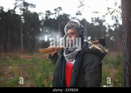 Junger Mann mit Axt über der Schulter im Wald Stockfoto