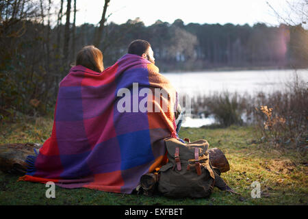Junges Paar am See bei Sonnenuntergang in Decke gehüllt. Stockfoto