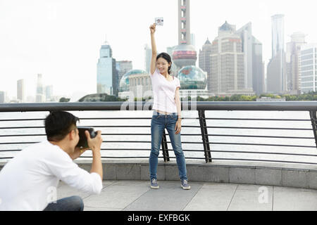 Weibliche Touristen halten Sofortbild posieren für Freund mit instant Kamera, Bund, Shanghai, China Stockfoto