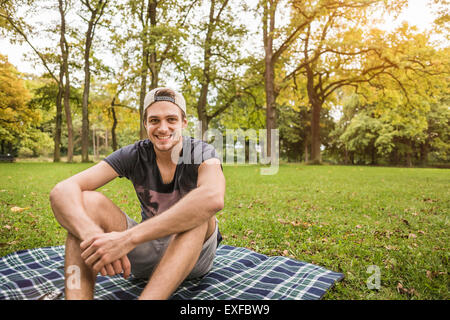 Porträt des jungen Mann sitzt auf der Picknickdecke im park Stockfoto