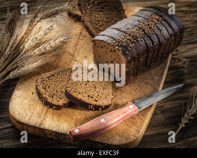 In Scheiben Schwarzbrot auf der alten Holzbrett. Stockfoto