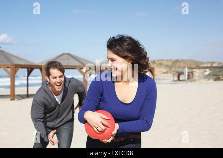 Junges Paar laufen mit Ball am Strand, Tel Aviv, Israel Stockfoto