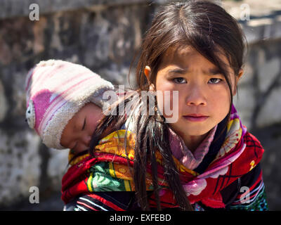 Nicht identifizierte Hmong Mädchen Baby tragen und tragen traditionelle Kleidung in Sapa Stadt, Lao Cai, Vietnam. Stockfoto